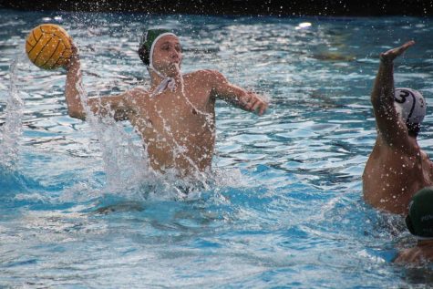 Senior Ben McAulay pushes out of the water to shoot over his opponent to score a goal.
