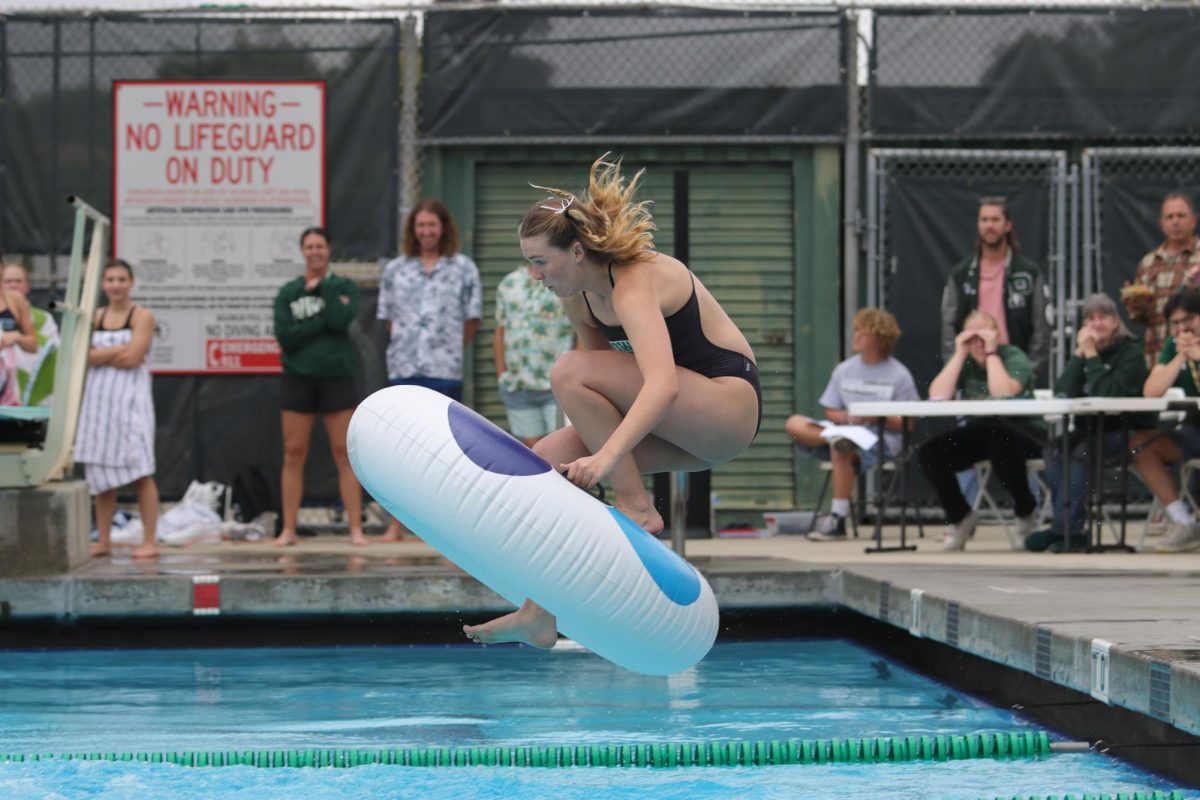In the air! Senior Paige McFadden leaps into the pool ahead of the race.