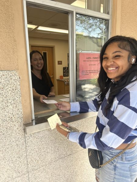 Sophomore Measya Heard picks up a slip from Cynthia Magana in the attendance office to get checked out of school.
