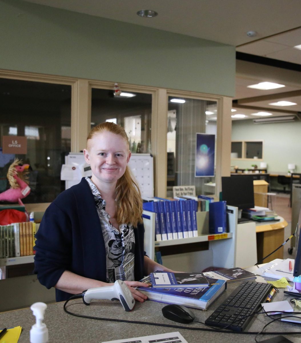 Ready to help: Morris poses with a smile and some books at the front desk in the main library. She looks forward to joining her family in the Poway Unified community.       