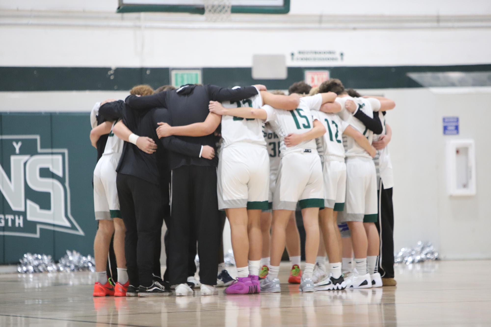 The Boy's Varsity Basketball team huddles together before the game.