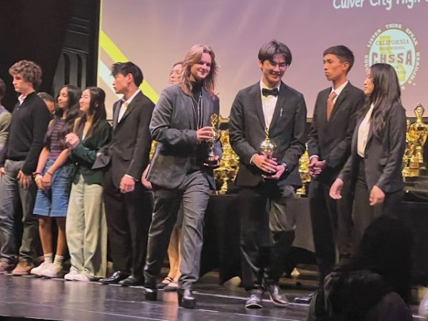 Walking with pride: Power duo junior Hannah Jones and senior Sherwood Kao smile greatly receiving trophies. Placing 11th out of 64 teams Jones and Kao hard work has payed off.