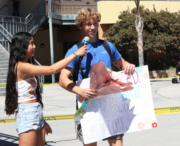 Junior Celeste Atienza helps senior Quinn Lerner “prom-pose” to his girlfriend by announcing it in front of the school with a sign and flowers. 
