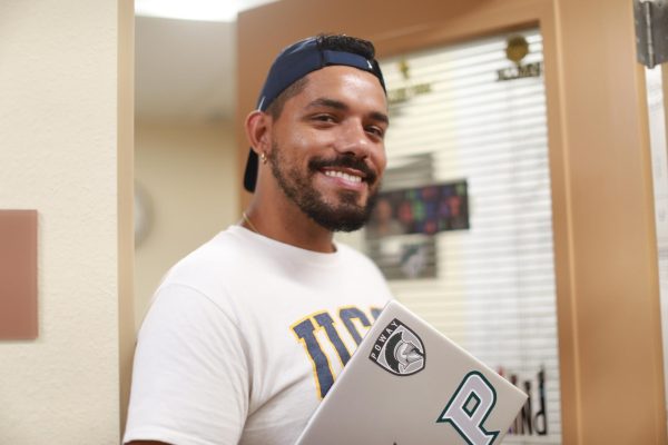 Assistant Principal Dominick Spylios smiles outside of his new office in a welcoming manner, proudly representing Titan pride.